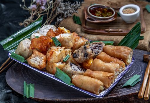 Many vegetarian food : Fried taro rolls (Taro Guangjian) and Deep fried spring rolls, Fried tofu, Fried radish, Fried taro and black beans (Zhu jiao quan or Fried taro cakes) Served with spicy sweet sauce and roasted crushed peanuts with wooden chopsticks on Ceramic dishes. Selective focus.