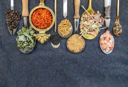 Various teas and dried herbs assortment on spoons in rustic style on balck background. Organic herbal, Selective focus, Copy space.