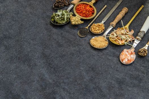 Various teas and dried herbs assortment on spoons in rustic style on balck background. Organic herbal, Selective focus, Copy space.