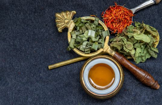 Wonderful Thai herbal tea with Dried pandan herb, indian marsh fleabane and safflower with honey on spoons. Selective focus.