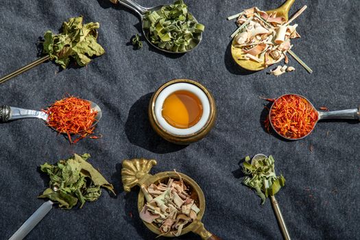 Various teas and dried herbs assortment on spoons in rustic style with honey on balck background. Organic herbal, Selective focus.