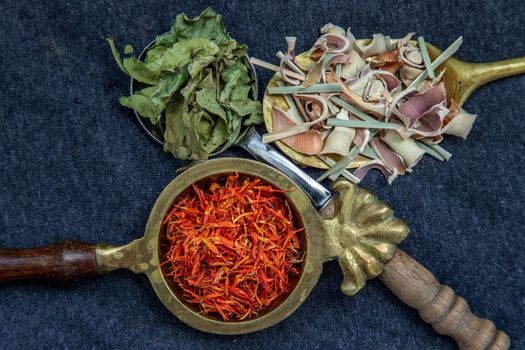 Wonderful Thai herbal tea with Dried lemongrass herb, indian marsh fleabane and safflower on spoons. Selective focus.