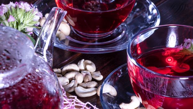 Hibiscus Red tea mug with carnation flowers close-up horizontal photo.English tea tradition.Medicinal therapy based on medicinal herbs and decoctions.Spicy herbs and medicinal broths.Elegant mugs