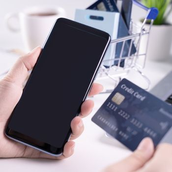 Office online paying, stay home shopping, electronic payment with credit card concept, laptop on white table background with shop cart, close up.