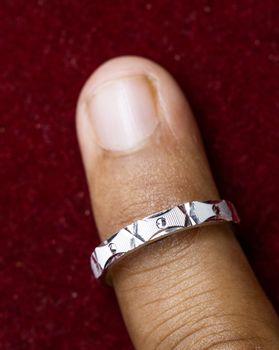 Wearing a round silver ring on red background