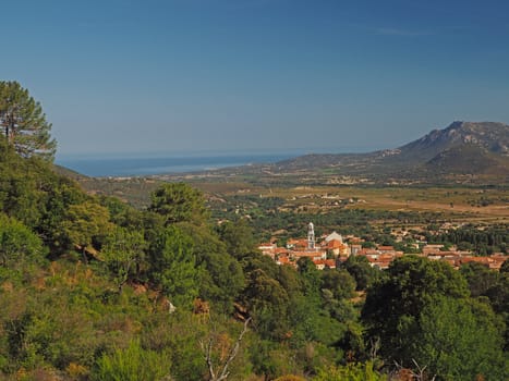 view on village, mountain and sea with green trees and blue sky