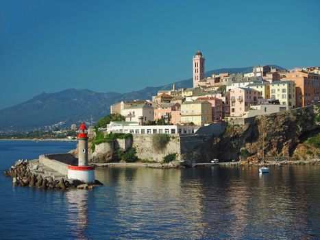 Corsica Bastia port view from sea on harbour with red lighthous church and old town blue sky background
