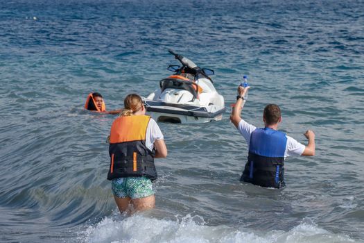 Tourists enjoy driving jet ski on the ocean. A young couple boardes a jetbike.