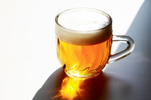 Mug of beer with foam on white background with shadow