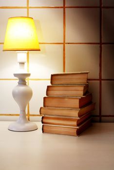 Elegance white desk lamp with yellow lampshade near stack of books