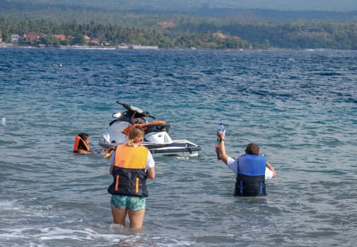 Tourists enjoy driving jet ski on the ocean. A young couple boardes a jetbike.