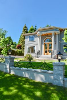 A perfect neighbourhood. Luxury family house with concrete driveway and garage on back yard on blue sky background