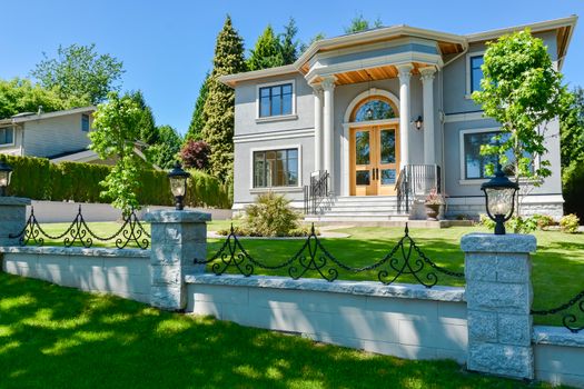 A perfect neighbourhood. Luxury family house with concrete driveway and garage on back yard on blue sky background