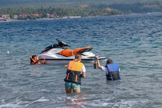 Tourists enjoy driving jet ski on the ocean. A young couple boardes a jetbike.