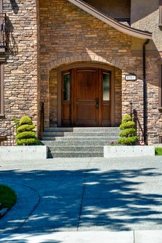 Entrance door of luxury family house with concrete door steps and decor trees by sides
