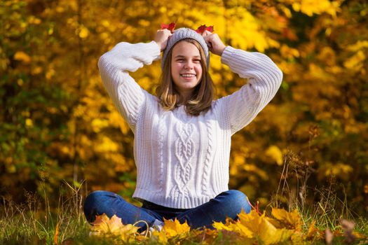 Portrait of pretty nice teenage girl sitting in autumn park , background with copy space for text