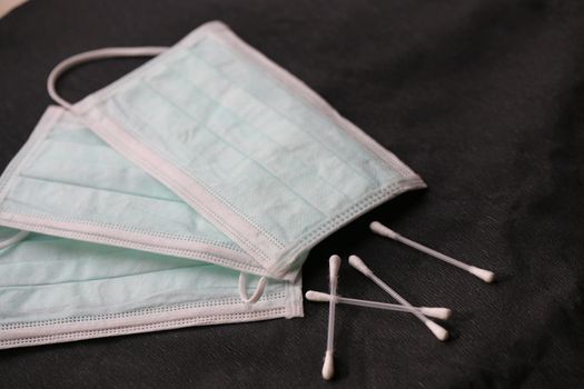 Three Facemasks with cottonbuds on a black surface