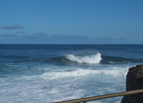 BIg crushing white wave over the Atlantic Ocean seen from terrace at la Fajana, La Palma, Canary Islands, Spain. Blue sky background