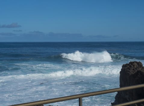 BIg crushing white wave over the Atlantic Ocean seen from terrace at la Fajana, La Palma, Canary Islands, Spain. Blue sky background