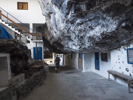 Tourist man at Cueva de Candelaria, Pirate cave Poris de Candelaria, small fisherman village hidden under rock cornice with white blue houses, attraction near Tijarafe, La Palma, Canary islands, Spain.
