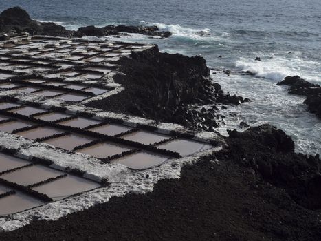 View of Fuencaliente salinas or saltworks and volcanic rock field and ocean coast. La Palma, Canary Islands. Ocean, blue sky wh