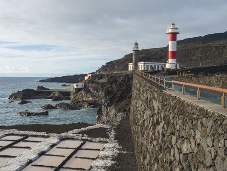 View of Fuencaliente salinas or saltworks and two lighthouse, old stone and white-red striped with volcanic rock field. La Palma, Canary Islands. Ocean, blue sky white clouds