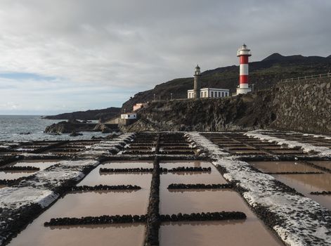 View of Fuencaliente salinas or saltworks and two lighthouse, old stone and white-red striped with volcanic rock field.La Palma, Canary Islands. Ocean, blue sky white clouds