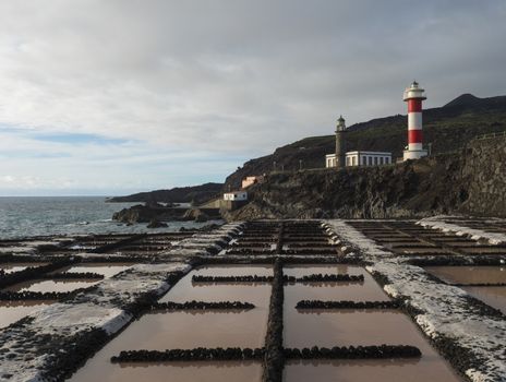 View of Fuencaliente salinas or saltworks and two lighthouse, old stone and white-red striped with volcanic rock field.La Palma, Canary Islands. Ocean, blue sky white clouds