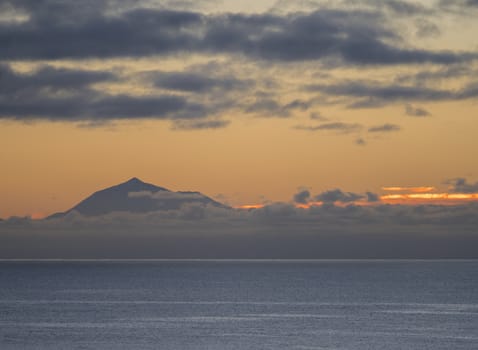 Beautiful orange sunrise over calm ocean and mountain pico del Teide at Tenerife seen from La Palma, Canary Island.