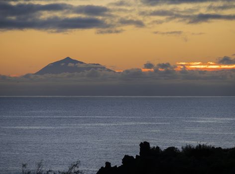 Beautiful orange sunrise over calm ocean and mountain pico del Teide at Tenerife seen from La Palma, Canary Island.