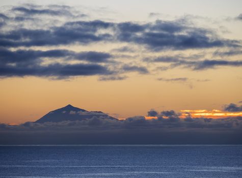 Beautiful orange sunrise over calm ocean and mountain pico del Teide at Tenerife seen from La Palma, Canary Island.