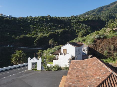 Old traditional houses at village Las Nieves with green mountains and subtropical vegetation, blue sky background. La Palma, Canary Islands