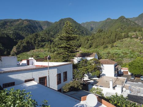 Old traditional houses at village Las Nieves with green mountains and subtropical vegetation, blue sky background. La Palma, Canary Islands