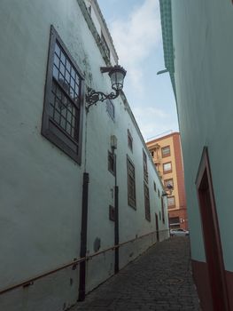 Empty narrow street at Santa Cruz de la Palma old city center with turquoise green traditional house, lantern and cobble stone paving. La Palma, Canary Islands, Spain.