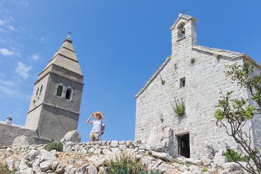 Female traveler sightseeing in an ancient costal village of Lubenice on the island of Cres, Croatia.