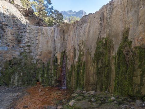 Cascada de Colores small allmost dry waterfall in a volcanic crater at Caldera de Taburiente, water stream is colorful colored by mineral water. La Palma, Canary Islands, Spain.