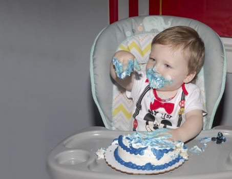 Toddler celebrating first birthday with smash cake.