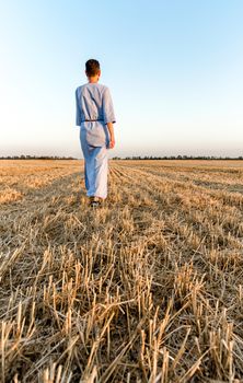 woman farmer walking away rear view of a mown wheat field in Ukraine