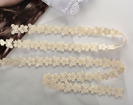 Tapes of beige gentle guipure, beauty lace fabric on light background. Elastic material. Using for Atelier and needlework store.