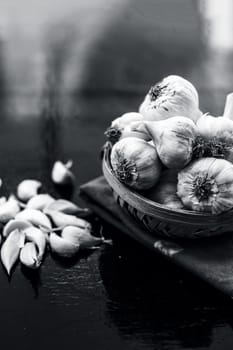 Raw organic garlic bulbs or lasun or Allium sativum in a hamper or basket on wooden surface.