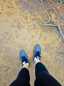 Sports shoes from a woman from above on African red floor.