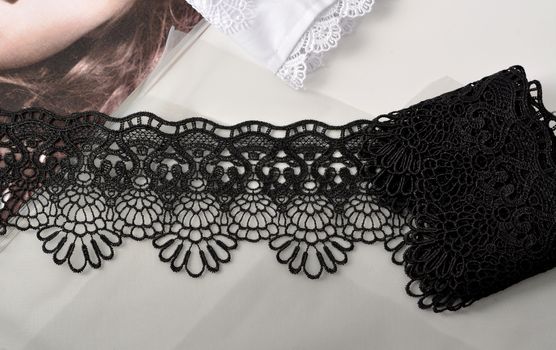 Tapes of black gentle guipure, beauty lace fabric on light background. Elastic material. Using for Atelier and needlework store.