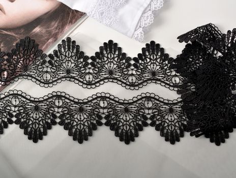 Tapes of black gentle guipure, beauty lace fabric on light background. Elastic material. Using for Atelier and needlework store.