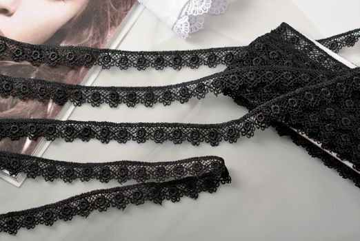 Tapes of black gentle guipure, beauty lace fabric on light background. Elastic material. Using for Atelier and needlework store.