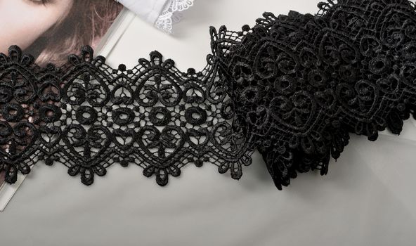 Tapes of black gentle guipure, beauty lace fabric on light background. Elastic material. Using for Atelier and needlework store.