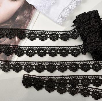 Tapes of black gentle guipure, beauty lace fabric on light background. Elastic material. Using for Atelier and needlework store.
