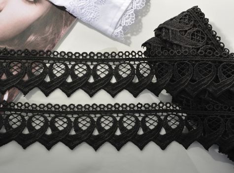Tapes of black gentle guipure, beauty lace fabric on light background. Elastic material. Using for Atelier and needlework store.