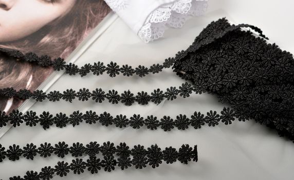 Tapes of black gentle guipure, beauty lace fabric on light background. Elastic material. Using for Atelier and needlework store.