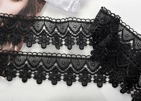 Tapes of black gentle guipure, beauty lace fabric on light background. Elastic material. Using for Atelier and needlework store.