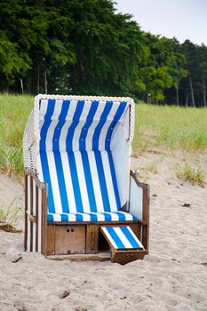 Wicker hooded beach chair in the sand on the beach of the Baltic Sea